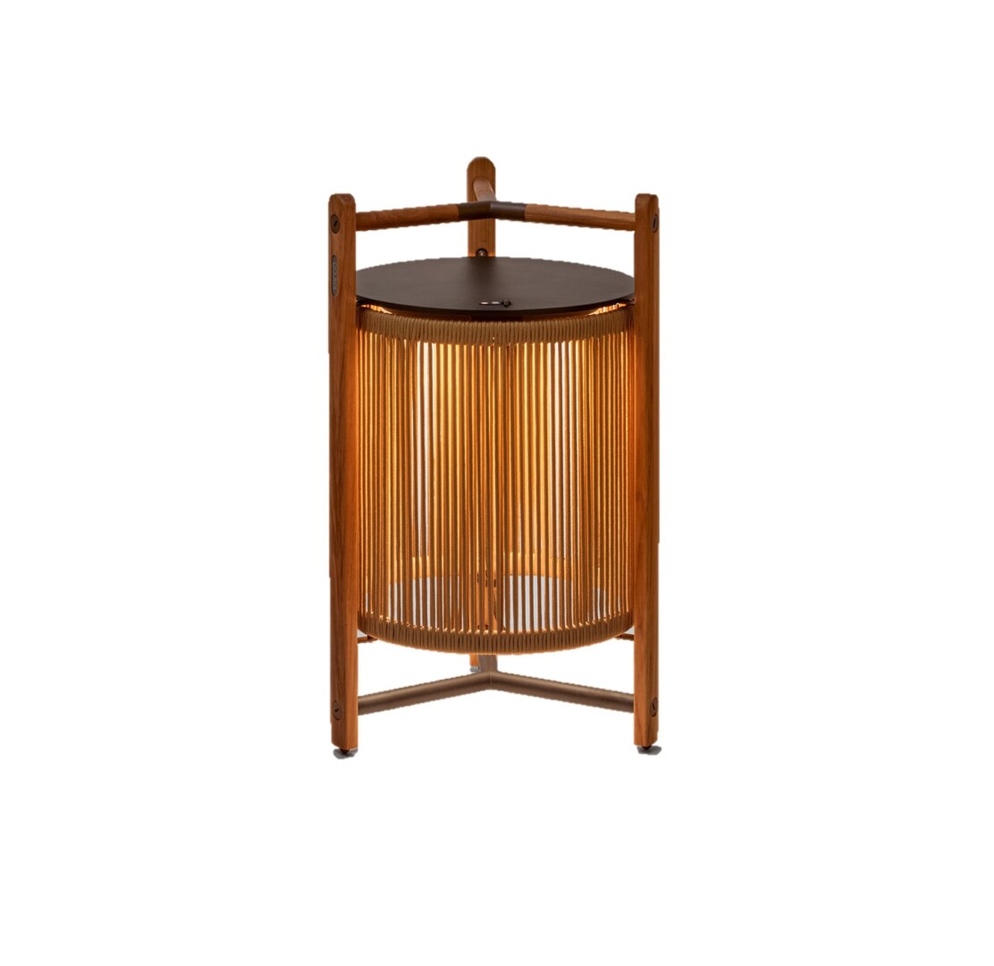 Kando P76R Outdoor_HB Eine moderne Tischlampe mit einer zylindrischen, geriffelten Schirmstruktur, umgeben von einem robusten dreibeinigen Rahmen aus Holz, der oben einen integrierten Griff aufweist. Die Lampe strahlt weiches Licht nach unten aus.