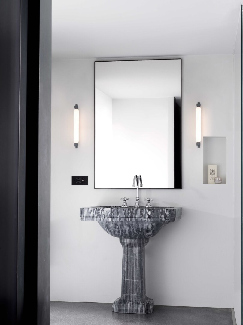 Zwei graue Wandleuchten La Roche, installiert im modernen Badezimmer, die ein sanftes, diffuses Licht auf beiden Seiten eines Spiegels abgeben.